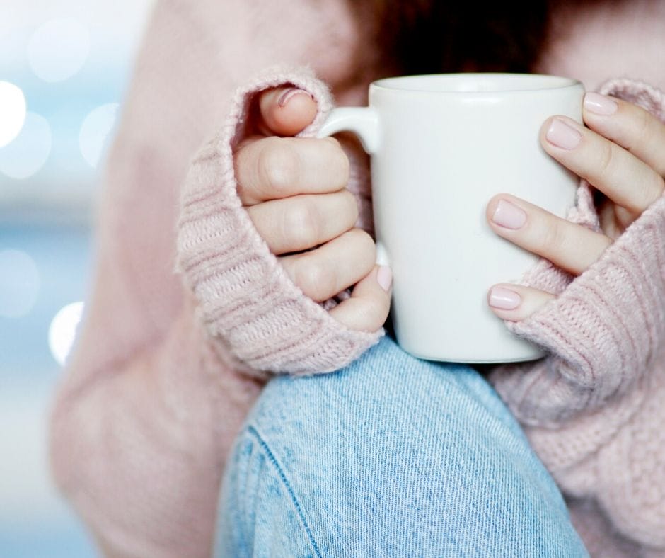 person holding a cup of hot tea resting on their knee