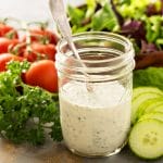 jar of homemade ranch dressing surrounded by crisp fresh veggies
