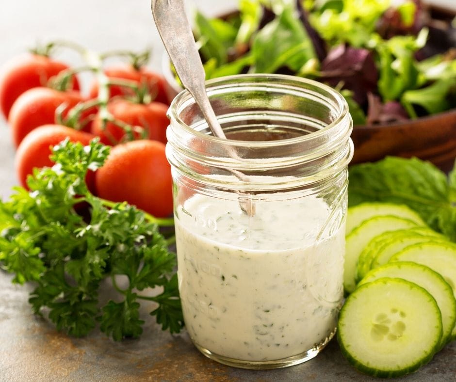 jar of homemade ranch dressing surrounded by crisp fresh veggies