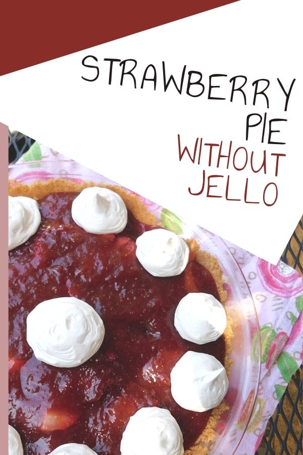 Fresh homemade strawberry pie on a napkin on the table. It's topped with dollops of homemade whipped cream.