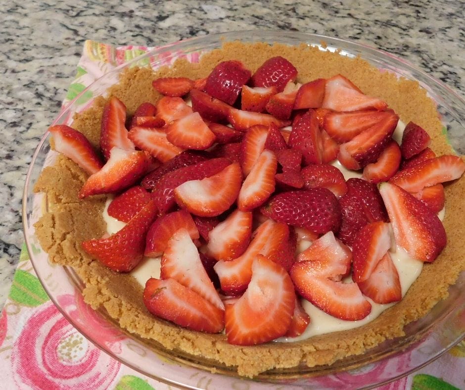 strawberries on top of cream cheese filling in a graham cracker crust