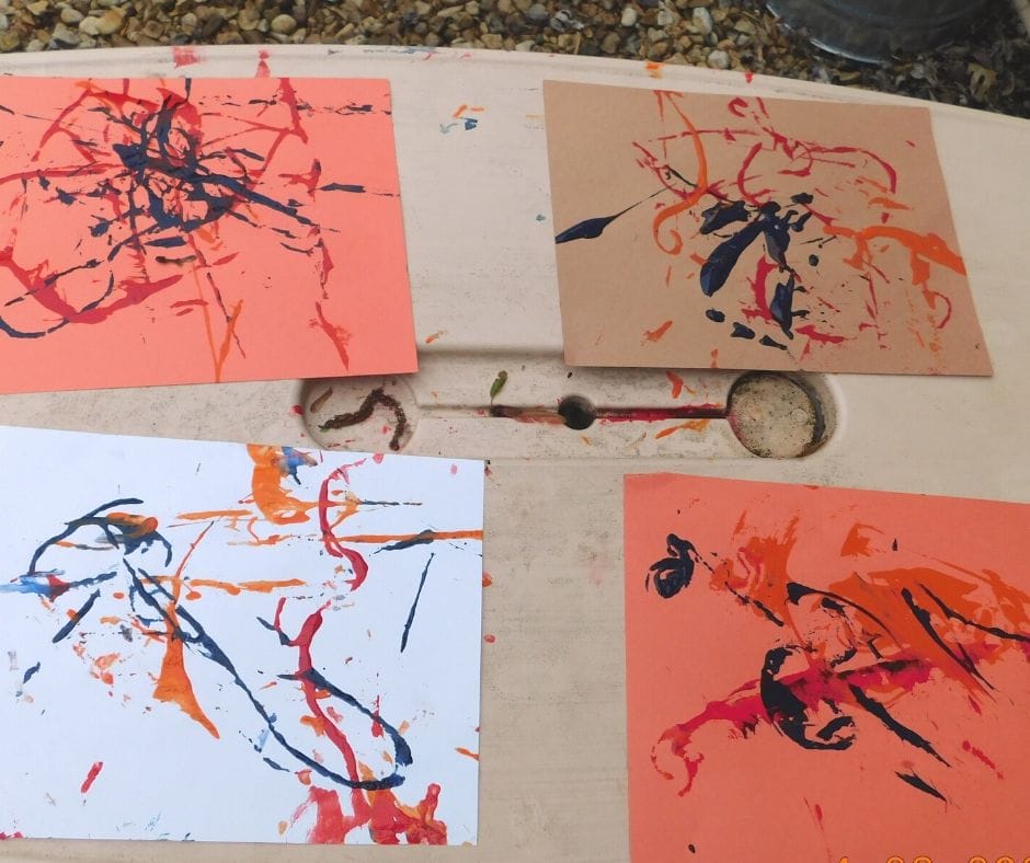 yarn paintings that kids have made on a table, 4 papers.