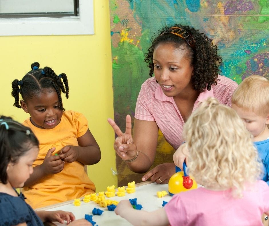 home daycare provider teaching kids at a table with counting bears