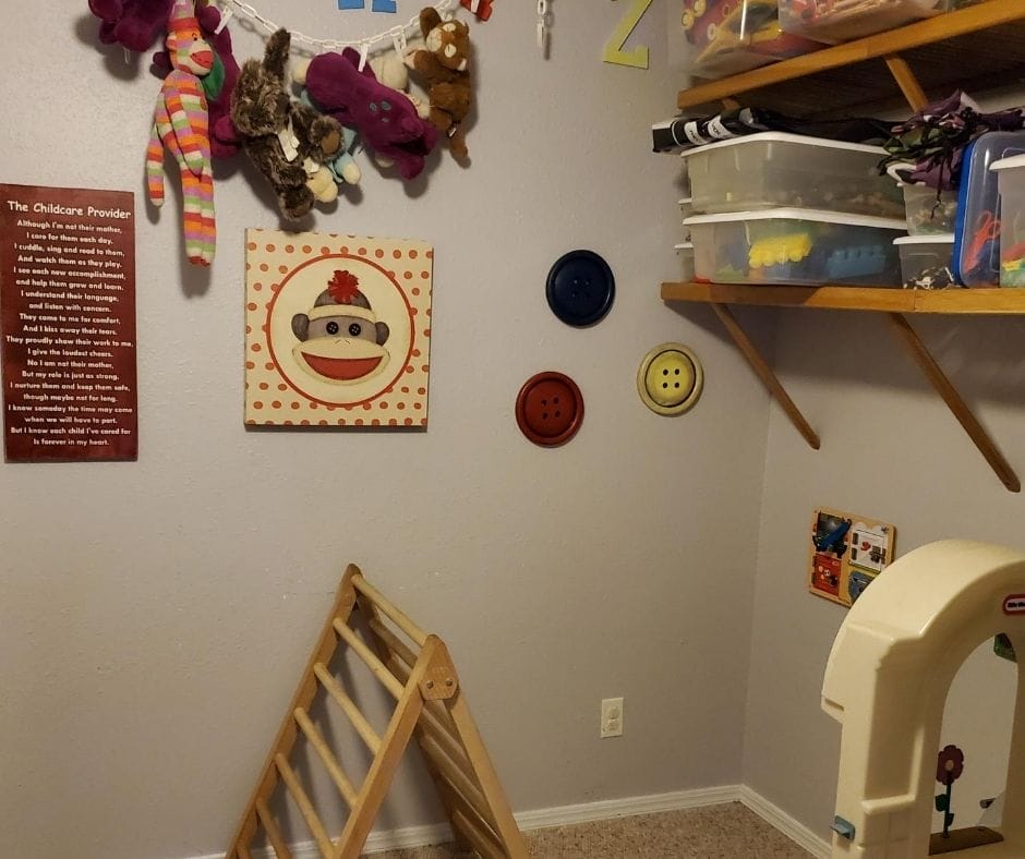 home daycare layout in playroom with pickler triangle, toy kitchen, stuffed animals on a chain and shelves full of toy sets