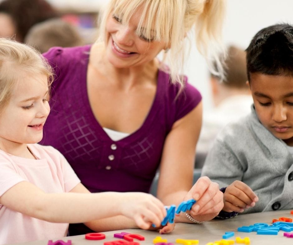 home daycare provider sitting at table teaching kids 