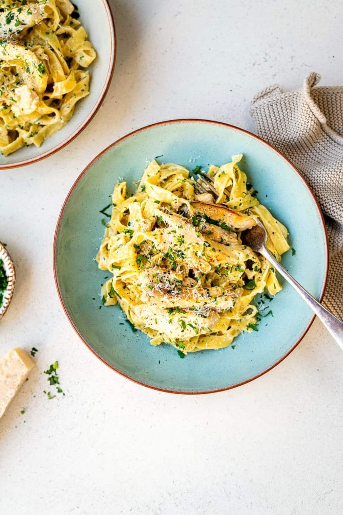 Chicken alfredo spun on a pretty blue plate with a fork. Great comfort food plate.