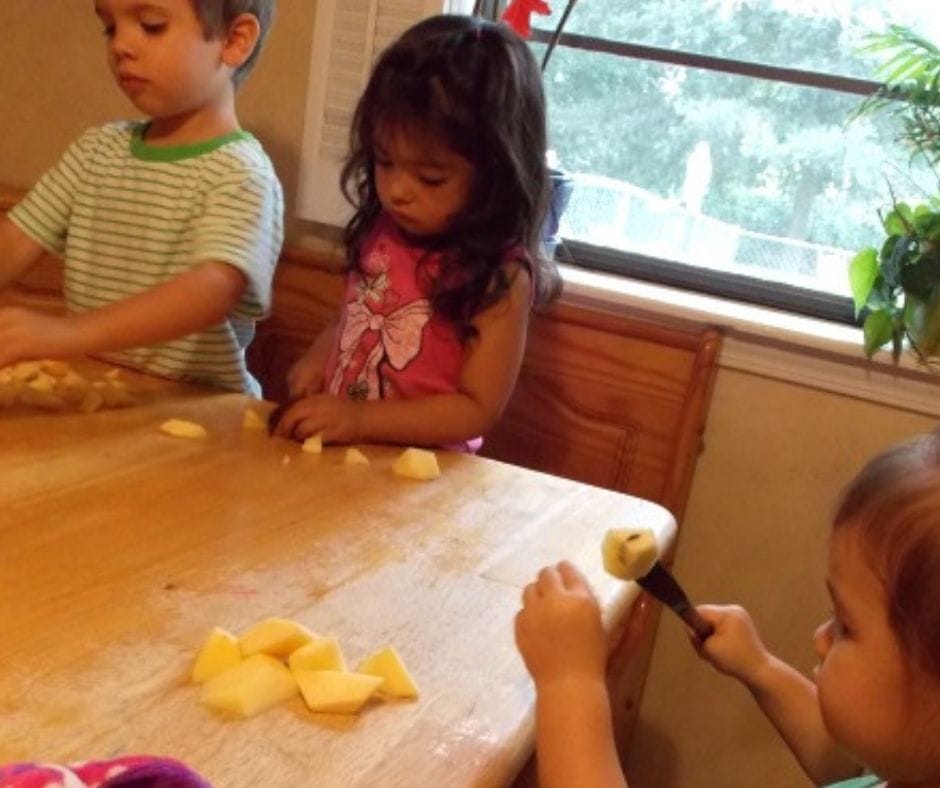 kids cutting up apples for applesauce in home daycare