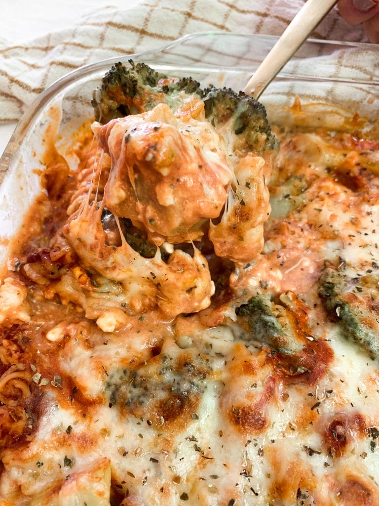 Cheesy lasagna bake comfort food casserole ith a spoon full being scooped up and oozing melty cheese.