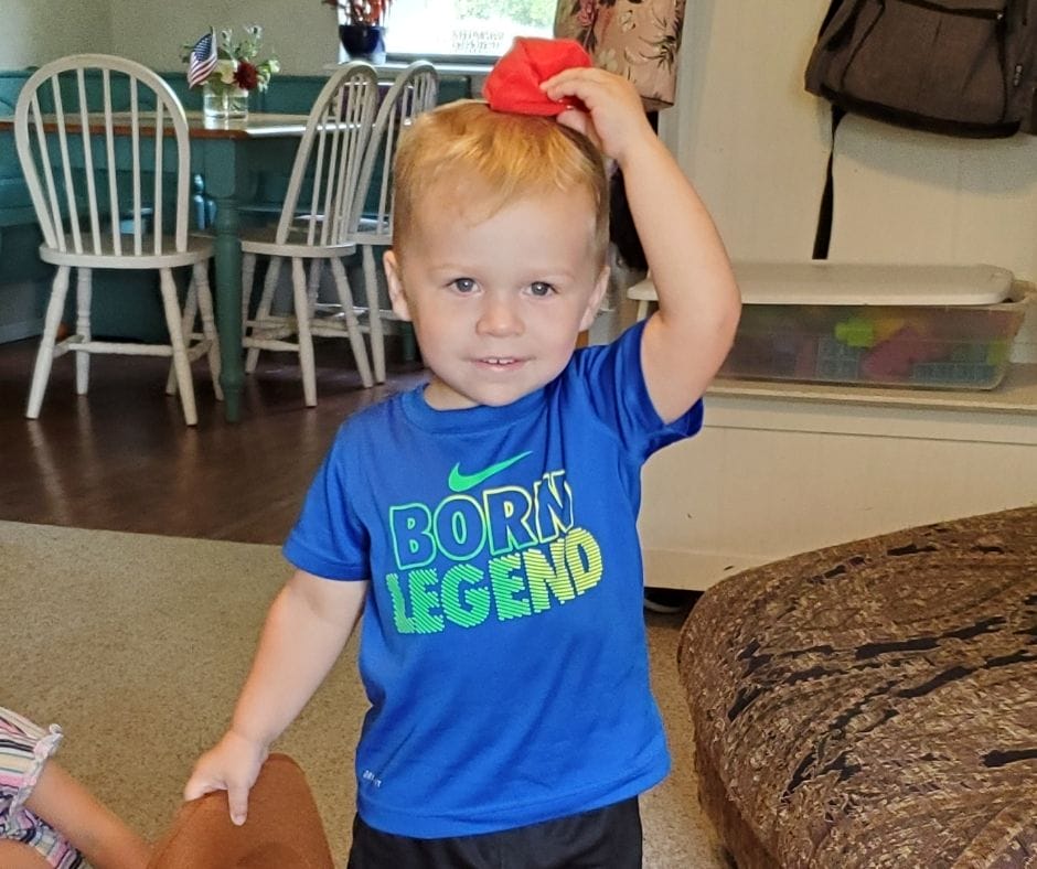 a child putting a cirlce bean bag on the top of his head