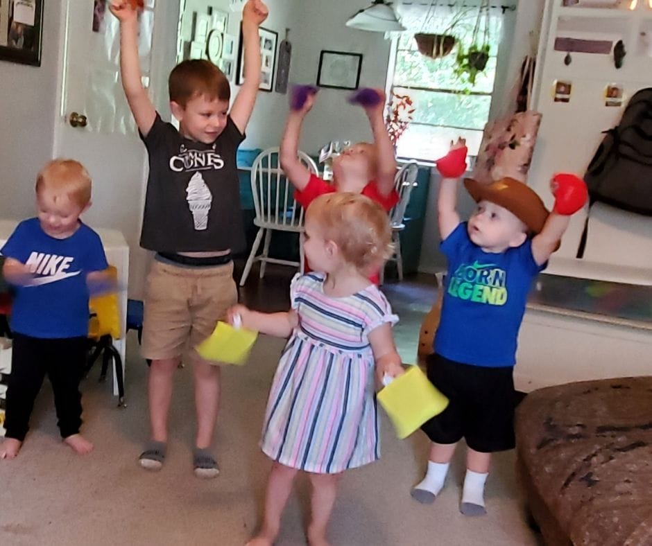 kids learning shapes with shape bean bags, playing a game where they lift their shapes into the air.