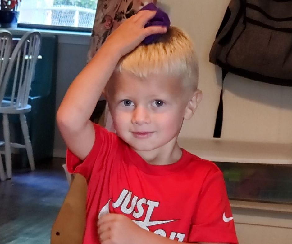 Child holding a bean bag on his head.