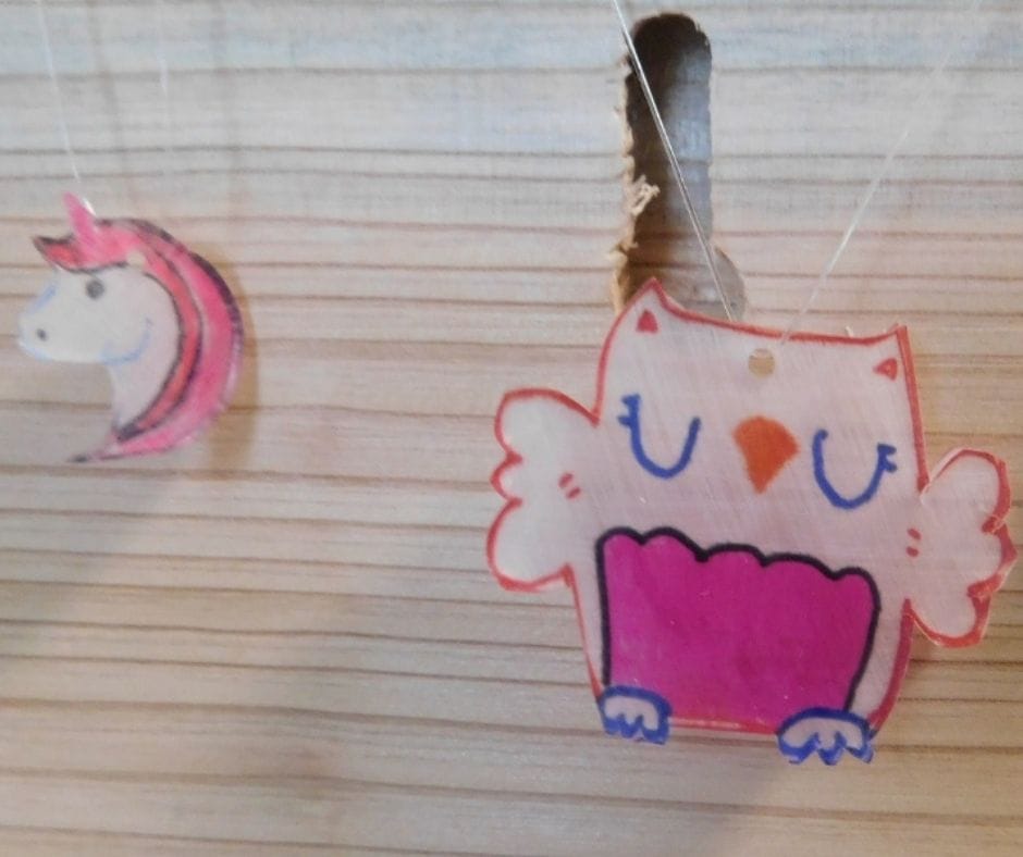 unicorn and owl homemade shrinky dink necklaces hanging on board