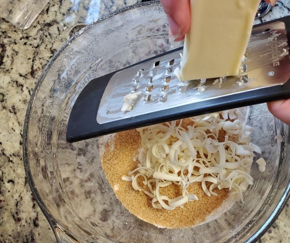 grating butter into a bowl of flour and sugar for old fashioned buttermilk biscuits
