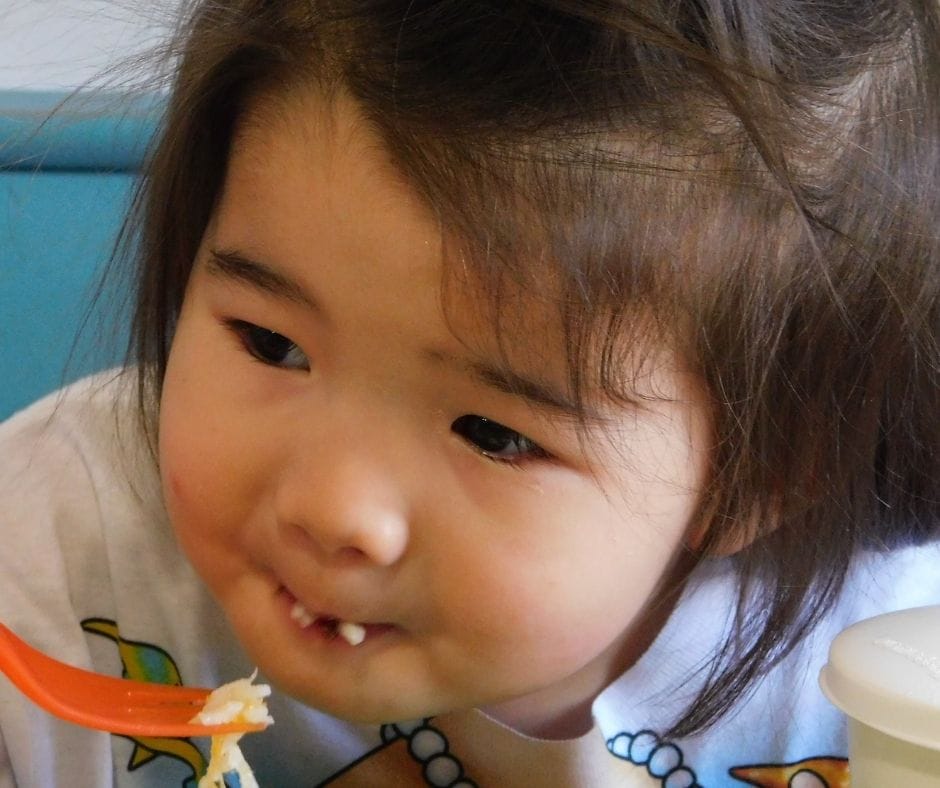 child eating snack with a fork at the table