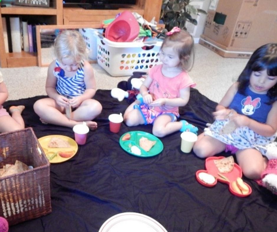 Kids eating snack on the floor at a picnic