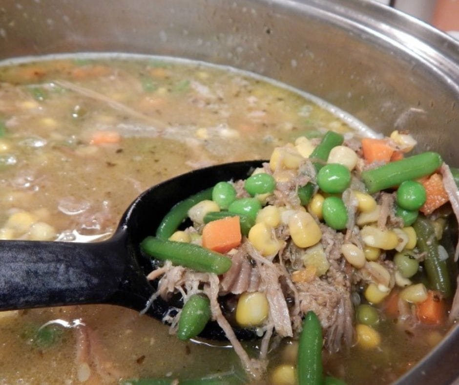 leftover pulled pork soup in a pot with a spoonfull pulled up