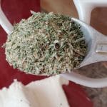 garlic bread seasoning mix in a spoon over a bowl of cream cheese