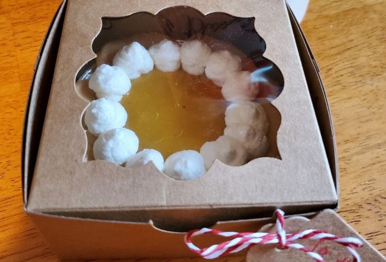 little 4 inch lemon mini tart in a brown cardboard box with plastic windwo and little red and white bow on the side