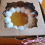 little 4 inch lemon mini tart in a brown cardboard box with plastic windwo and little red and white bow on the side
