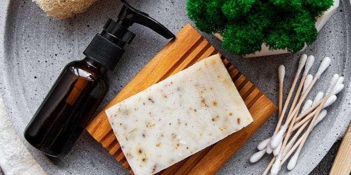 Soap and a pump on a bowl on the counter with qtips, luffa, and broccoli