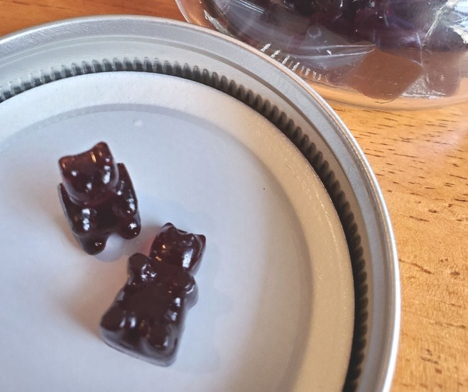 Elderberry gummies on the lid of a mason jar next to the jar on the table
