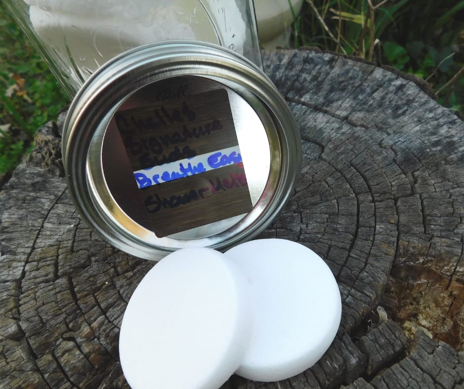 Shower vapor tablets and a jar sitting on the top of a stump