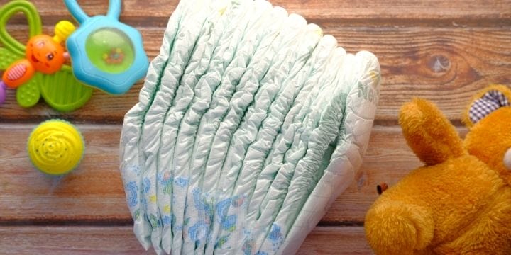 Stack of diapers, teddy bear, and rattles on a table