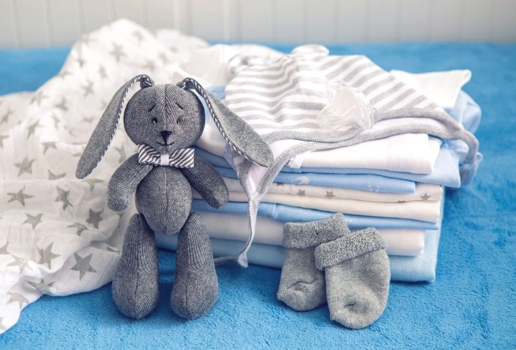 stack of baby onsies with socks and a stuffed bunny