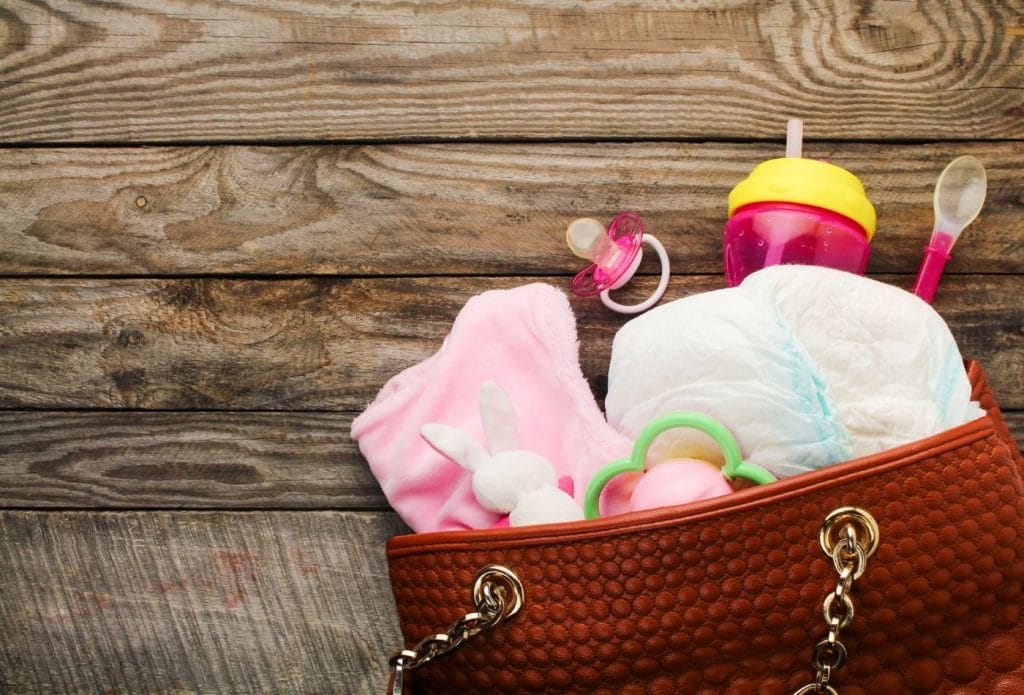 Diaper bag with cup, spoon, pacifier, change of clothes, diapers, and toys.