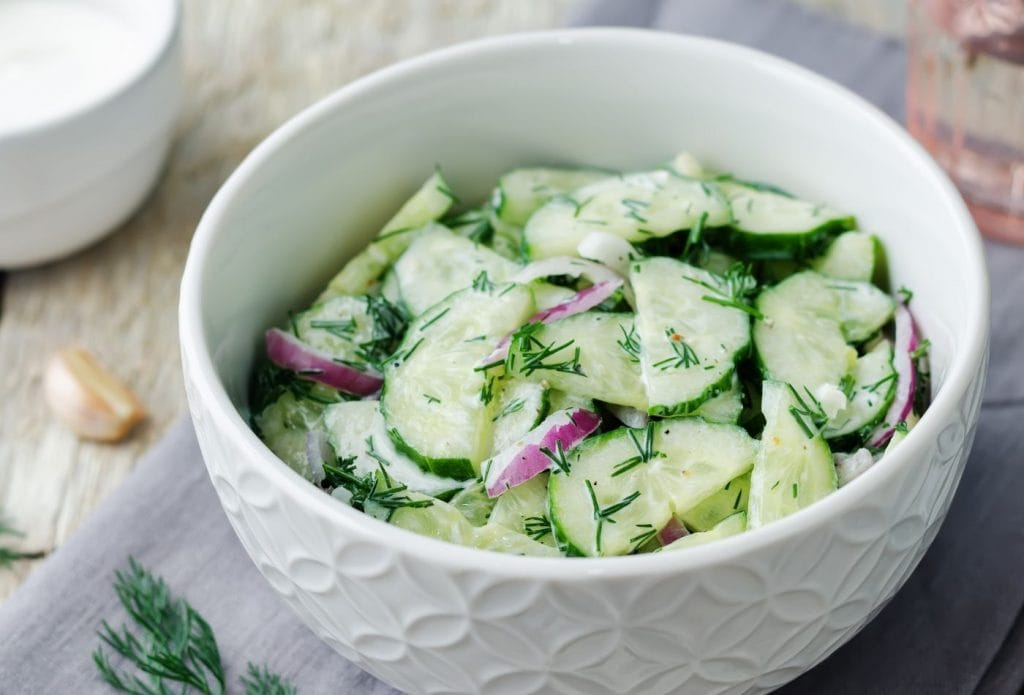 Creamy yogurt cucumber salad in a bowl with onions and dill. 