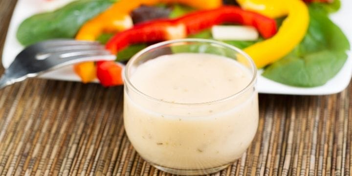 creamy cucumber salad dressing in a bowl in front of some sliced vegetables on a plate