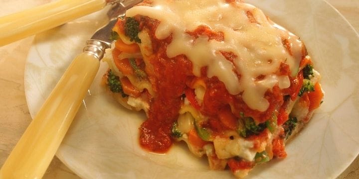 vegetable lasagna on a plate with a knife and a fork for meatless monday