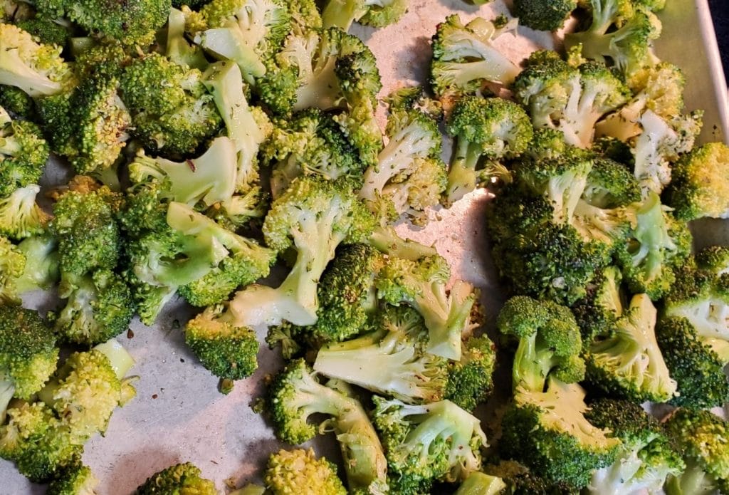 Raw broccoli cut up on a sheet tray ready to make broccoli recipe for kids