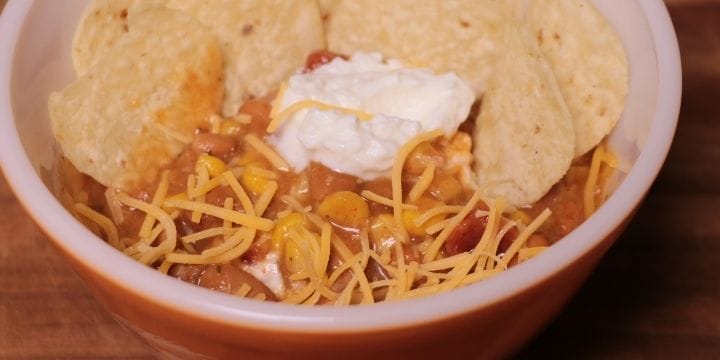 taco soup in a bowl with cheese, sour cream, and chips on top