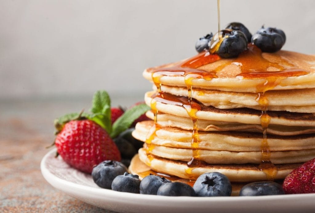 stack of pancakes with fruit and syrup for meatless monday breakfast