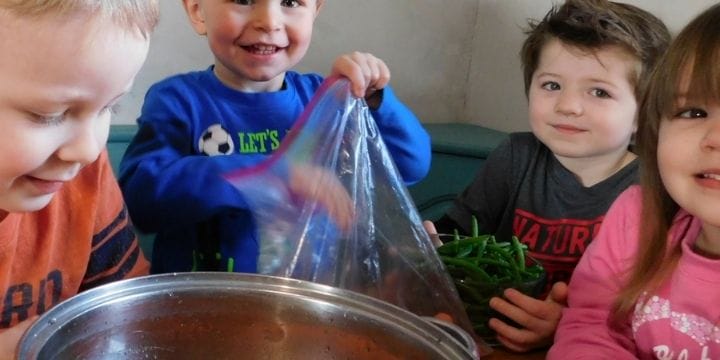 kids sharing vegetables they brought to make friendship soup in home daycare