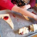 rolling ham and cranberry sauce in crescent roll dough