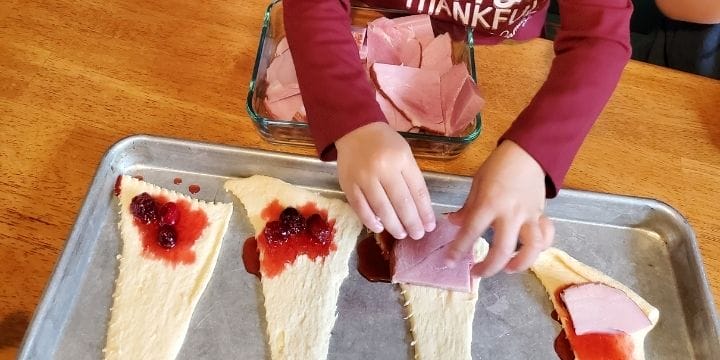 cranberry sauce and ham being rolled up in crescent roll dough