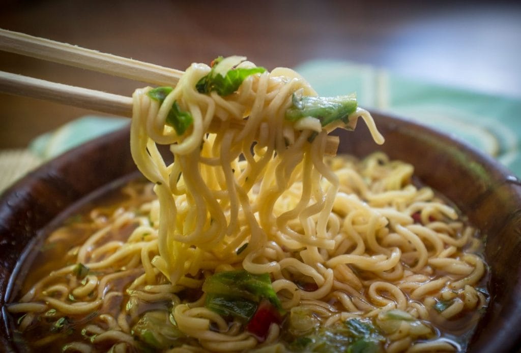 bowl of ramen with chops sticks pulling up a bite