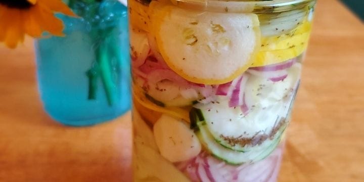 Pickled cucumbers and squash with onions in a jar on the table