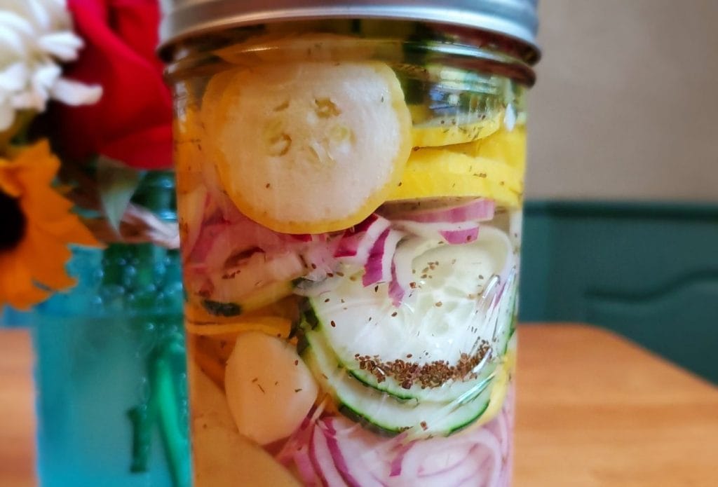 PIckled cucumber and squash with onions in a jar on the table