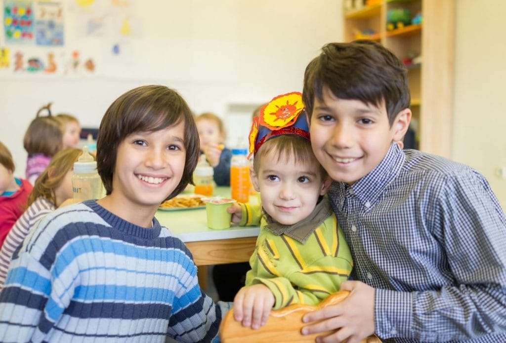 Mixed age group kids sitting at a lunch table together