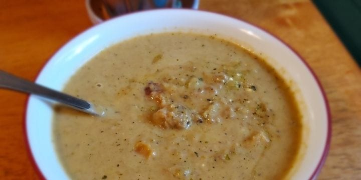 broccoli sweet potato pork soup in a bowl with a spoon
