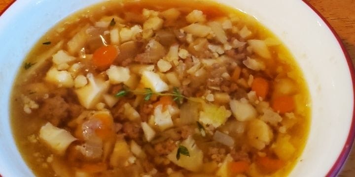 hamburger and cauliflower soup in a bowl with a garnish of thyme on top
