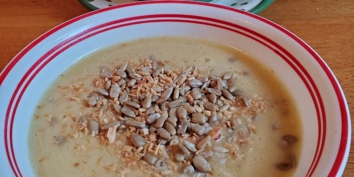 roasted summer squash soup in a bowl topped with roasted coconut and sunflower seeds