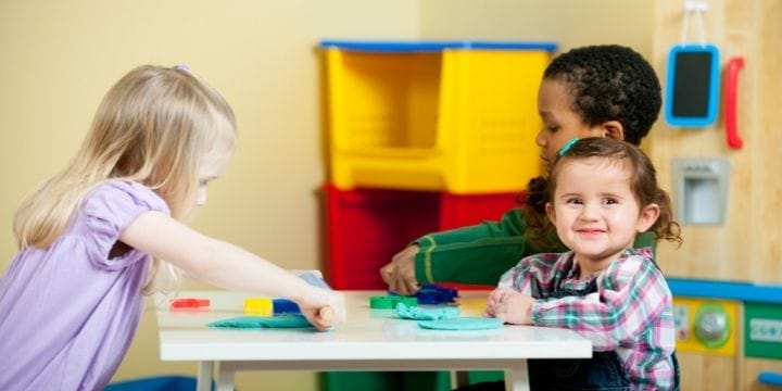 Older and younger kids playing at a table together in daycare