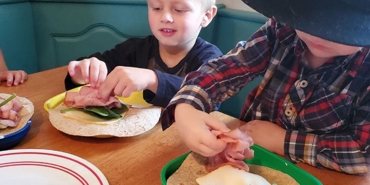 kids building tortilla roll ups at the table