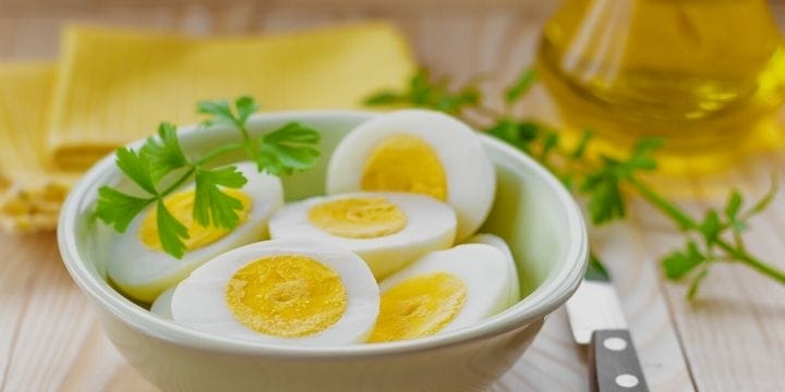 perfect boiled eggs sliced in half in a bowl with some parsley on the side