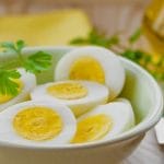 perfect boiled eggs sliced in half in a bowl with some parsley on the side