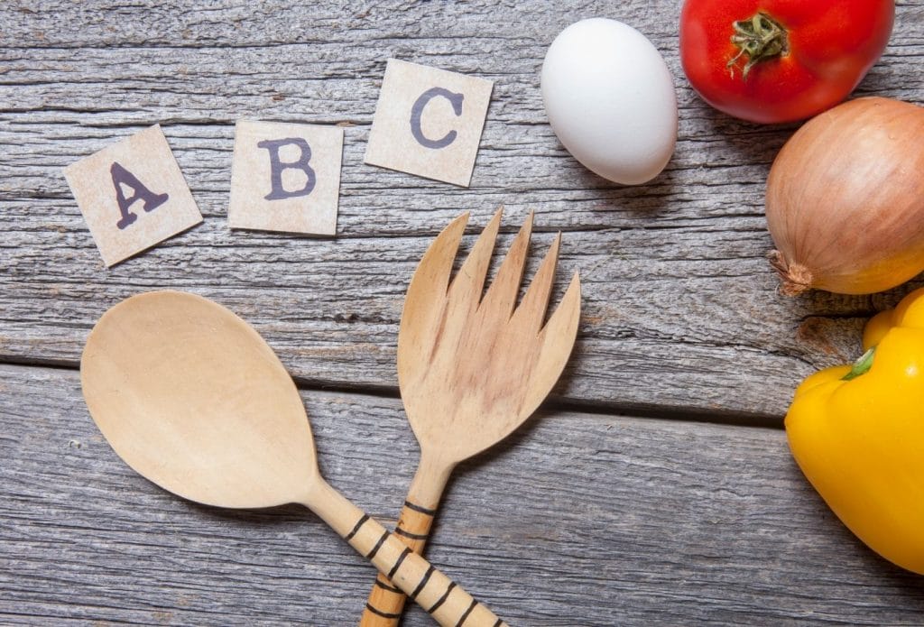 table with a b c and utensils, an egg and other beginning cooking items